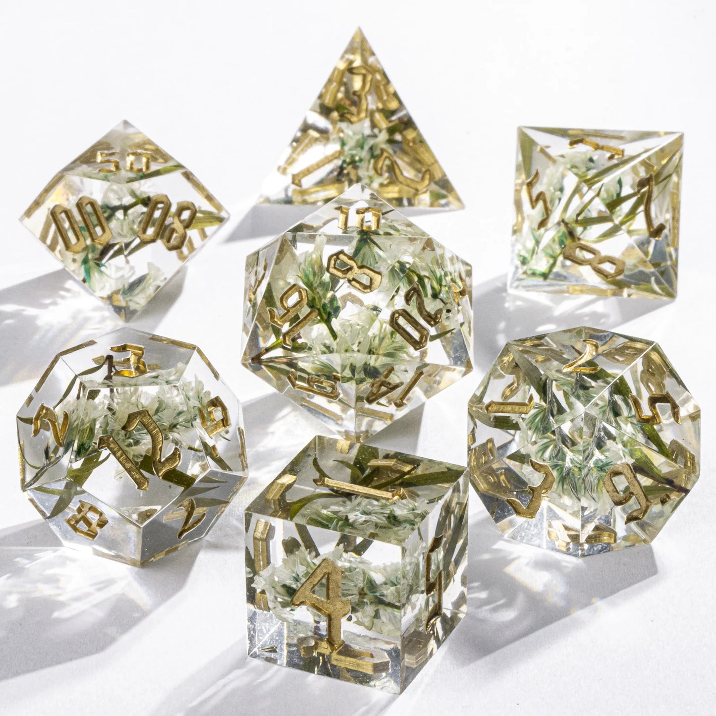 Set of clear polyhedral dice with gold numbers on a white background