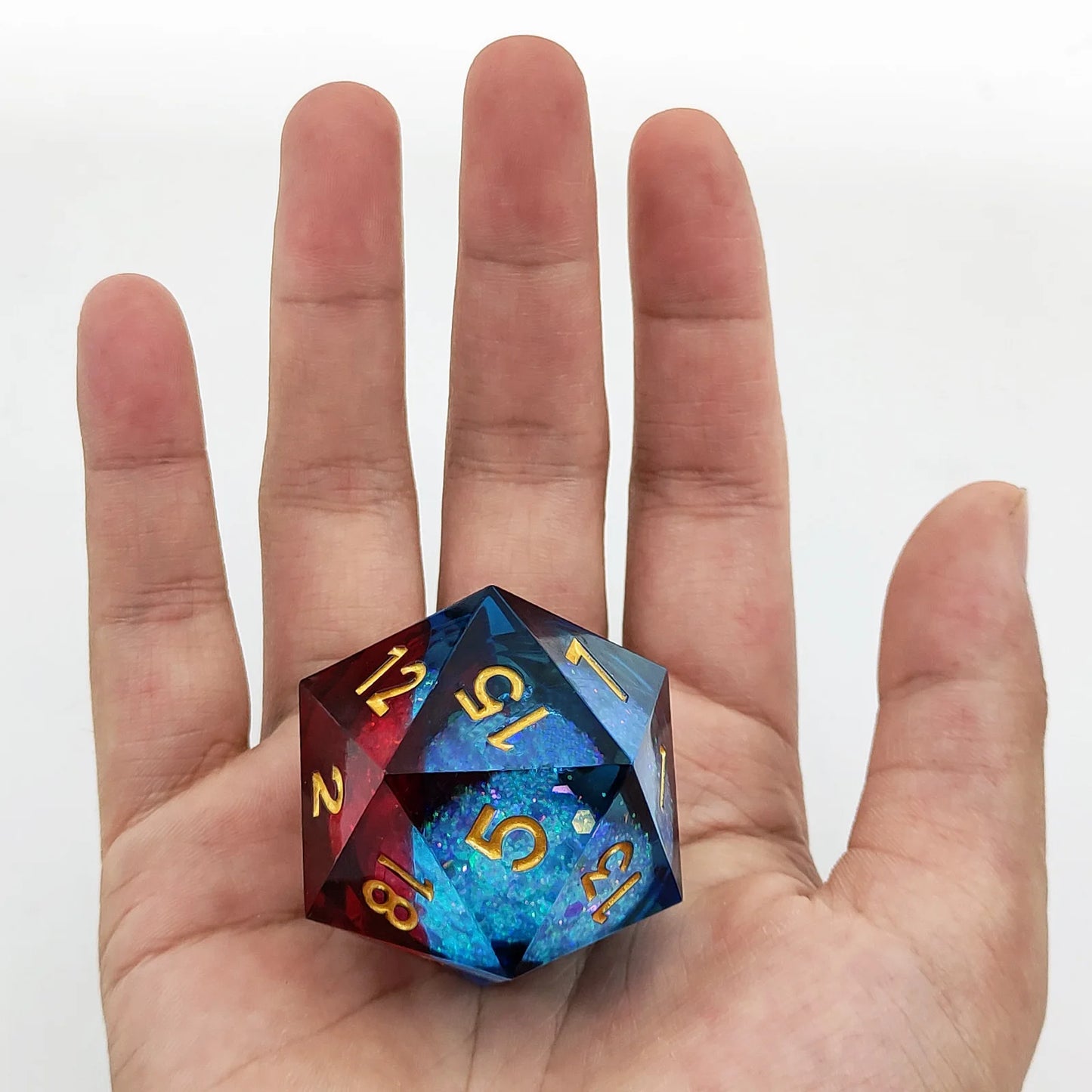 Multicolored die held in a hand against a white background