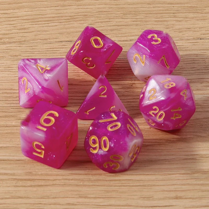 Set of pink dice with gold numbers on a wooden surface