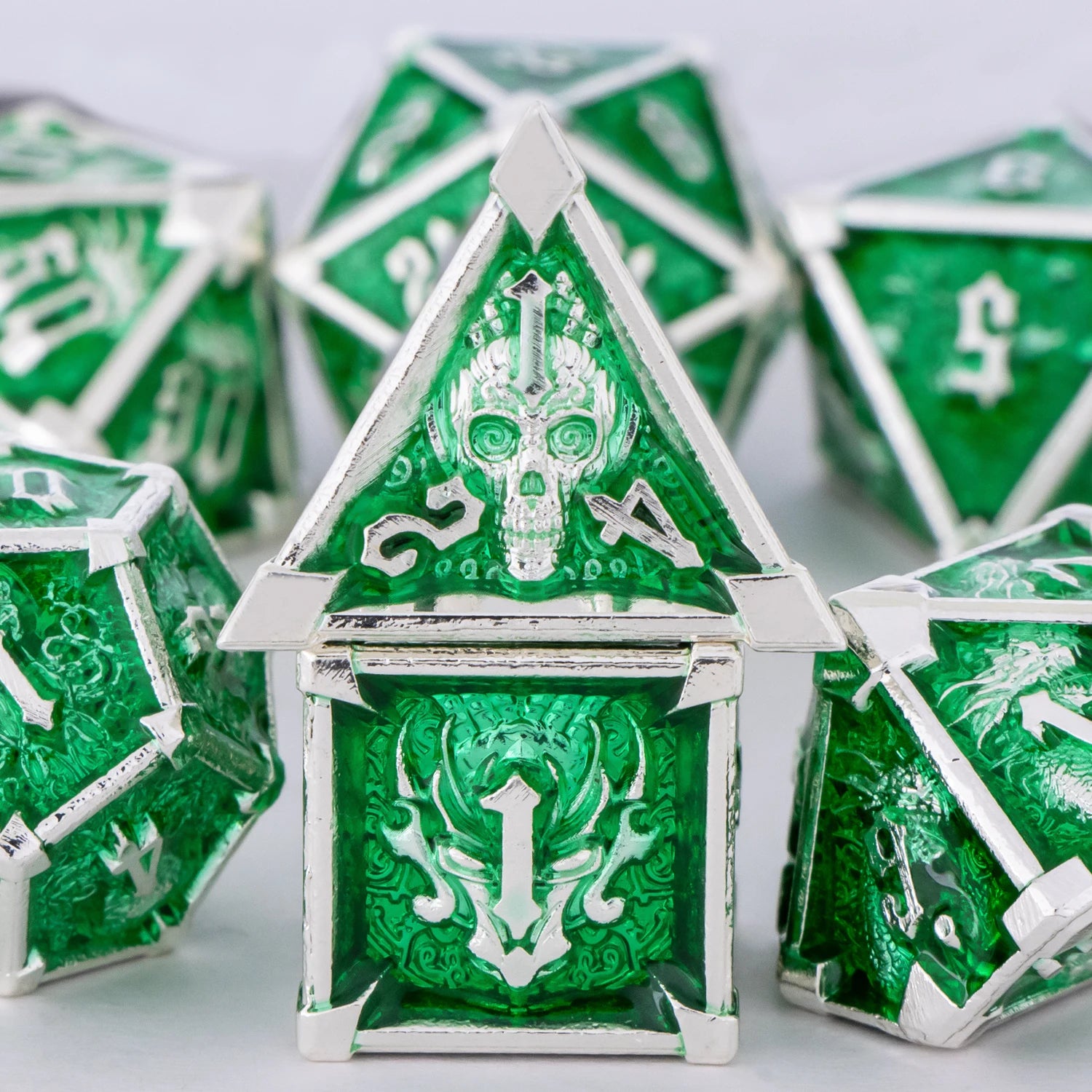 Green and silver polyhedral dice with intricate designs on a light gray background