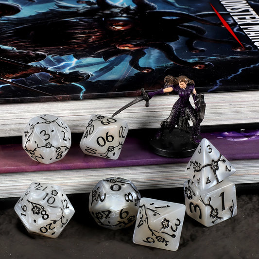 Set of 7 white dice with engraved black numbering, and flower motifs.