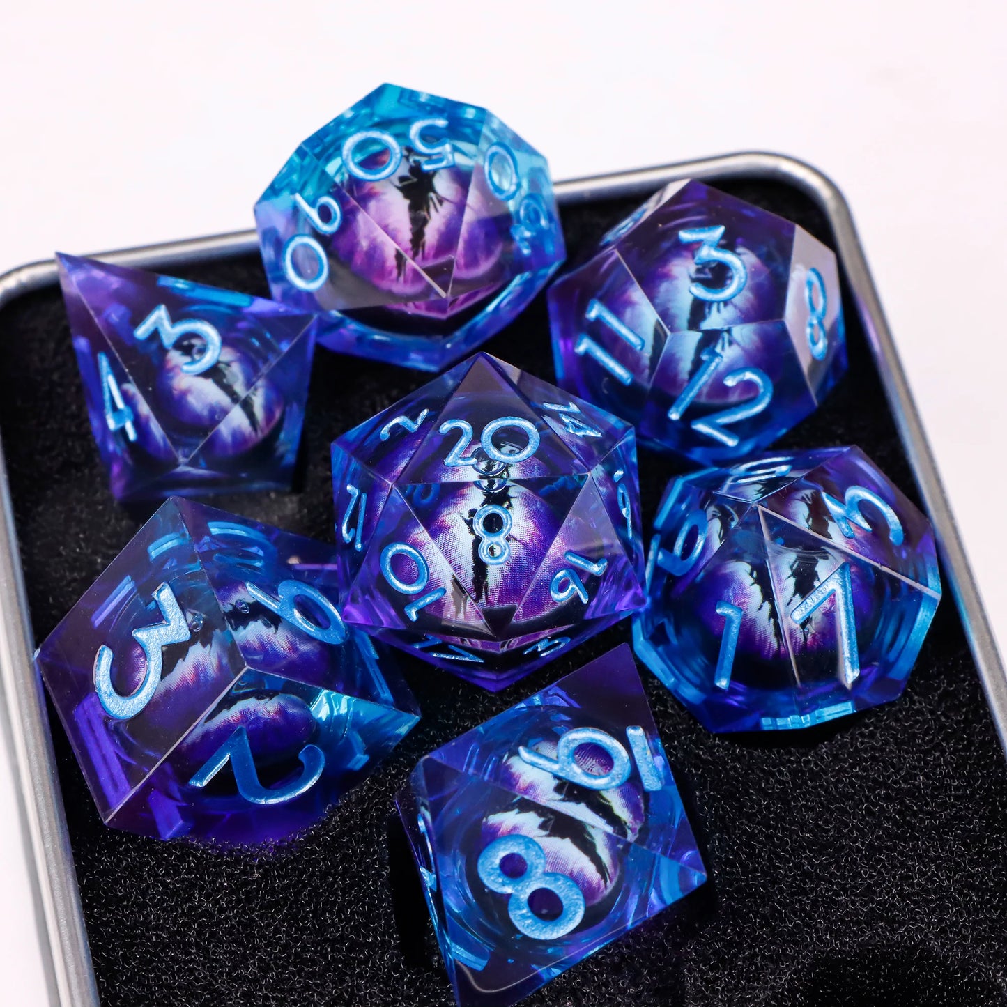 A set of blue and purple translucent ttrpg dice with blue numbering. Inside each die there is a liquid core, containing a fantasy eye staring upwards.