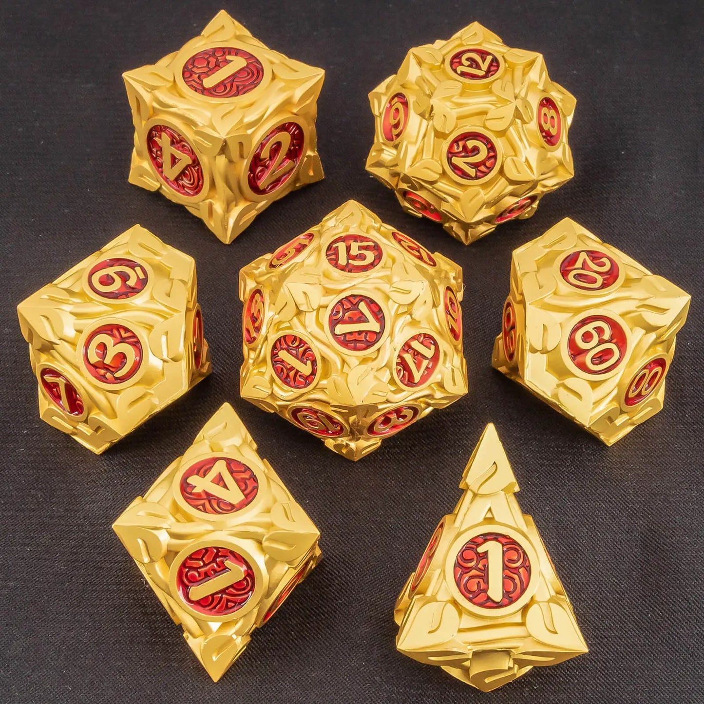 A set of metallic gold polyhedral gaming dice with red circular faces displaying ornate gold numbers, arranged on a dark textured background.
