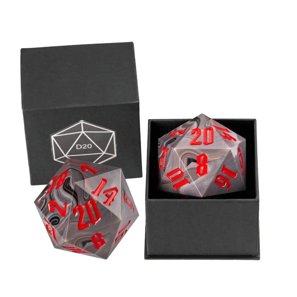 A clear acrylic D20 polyhedral die with red numbering, shown alongside a matching black gift box with a white D20 logo and another open box containing the die.