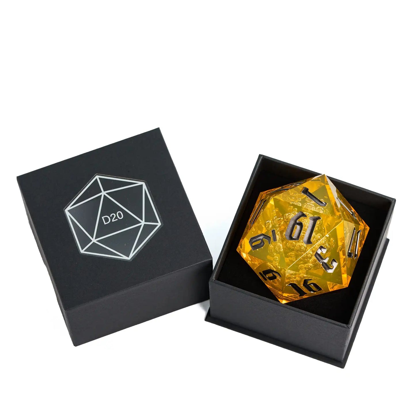 A translucent amber-yellow d20 polyhedral gaming die displayed inside an open black presentation box next to its closed lid, which features a white engraved D20 symbol.