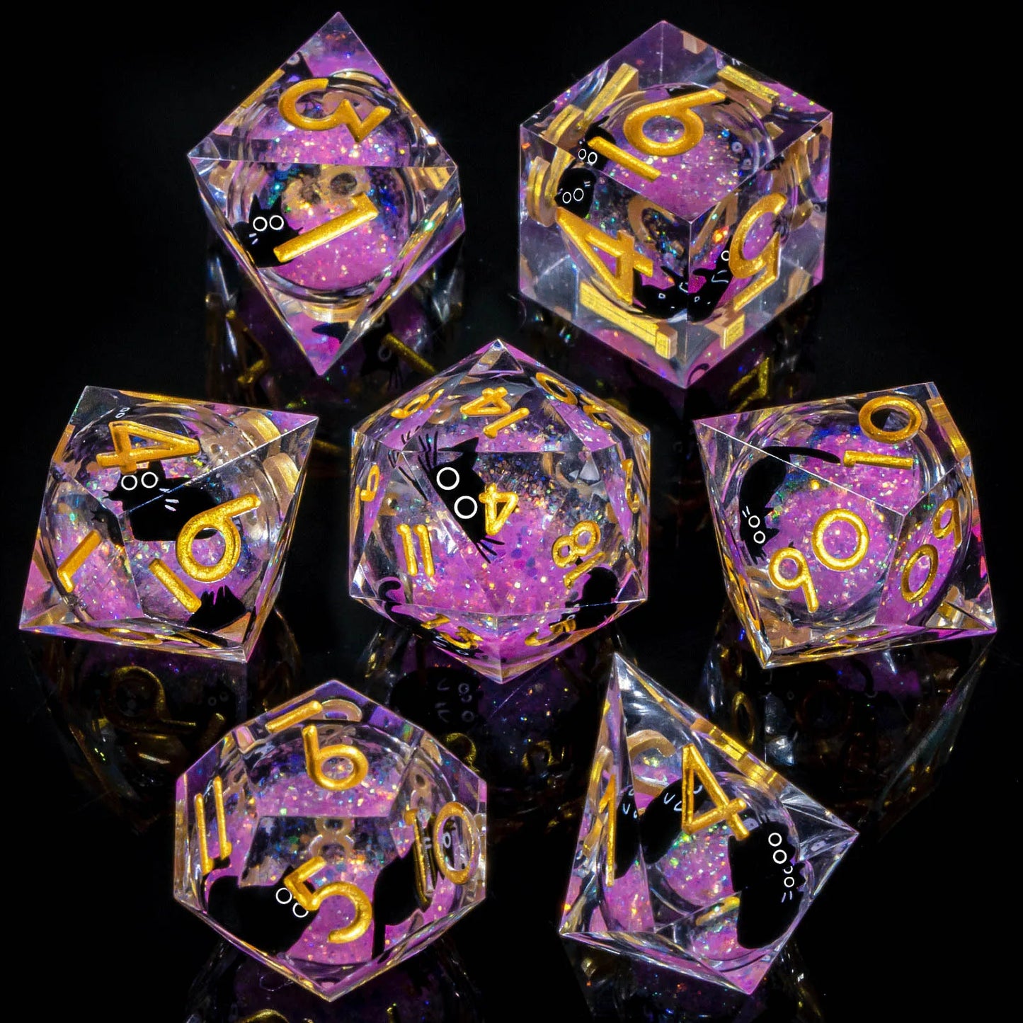 A set of transparent acryilic dice with a liquid core containiner pink glitter and cartoon cats, with gold numbering.