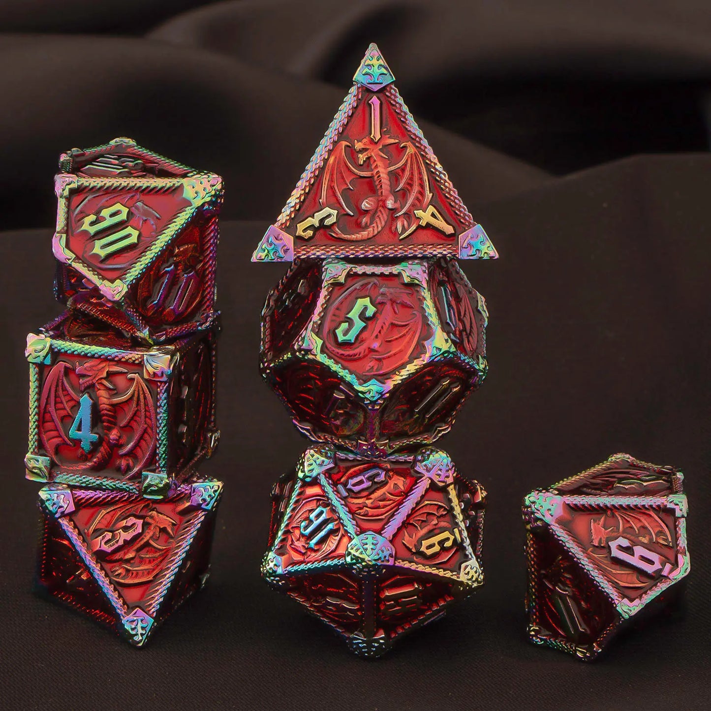 A set of metal red polyhedral gaming dice with rainbow iridescent edges and raised ornate detailing, arranged on a dark draped fabric background.
