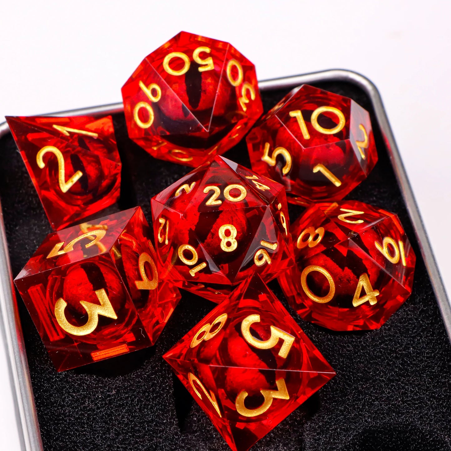 A set of red translucent ttrpg dice with gold numbering. Inside each die there is a liquid core, containing a fantasy eye staring upwards.