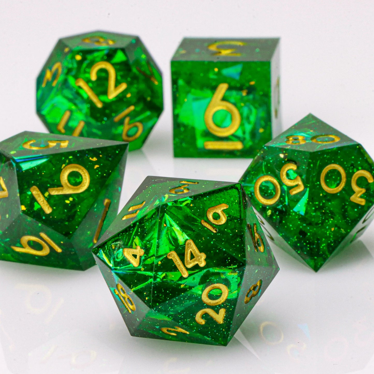 Set of green polyhedral dice with gold numbers on a white background