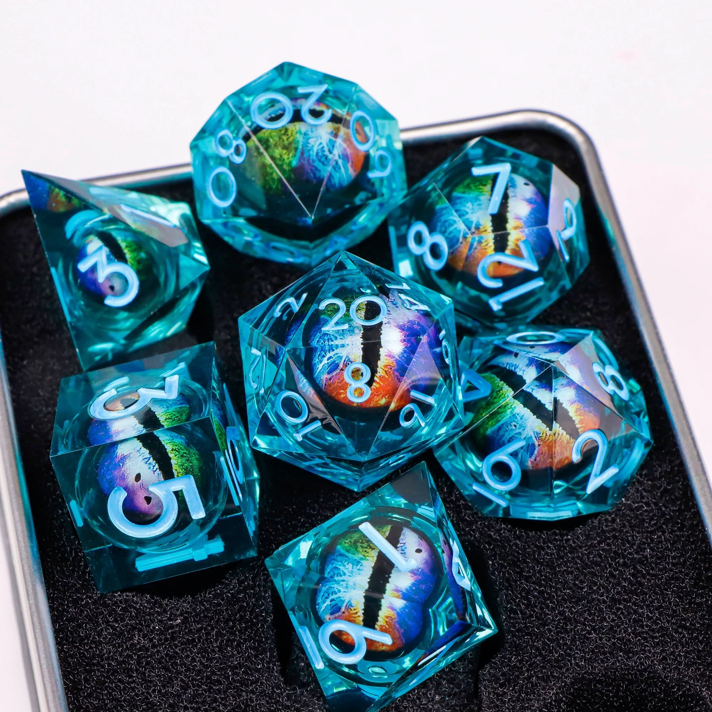 A set of blue translucent ttrpg dice with blue numbering. Inside each die there is a liquid core, containing a multicolored fantasy eye staring upwards.