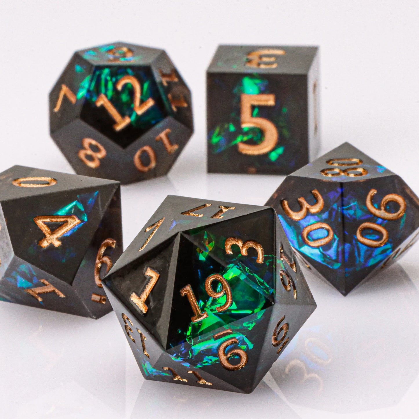 Set of black polyhedral dice with copper numbers on a white background
