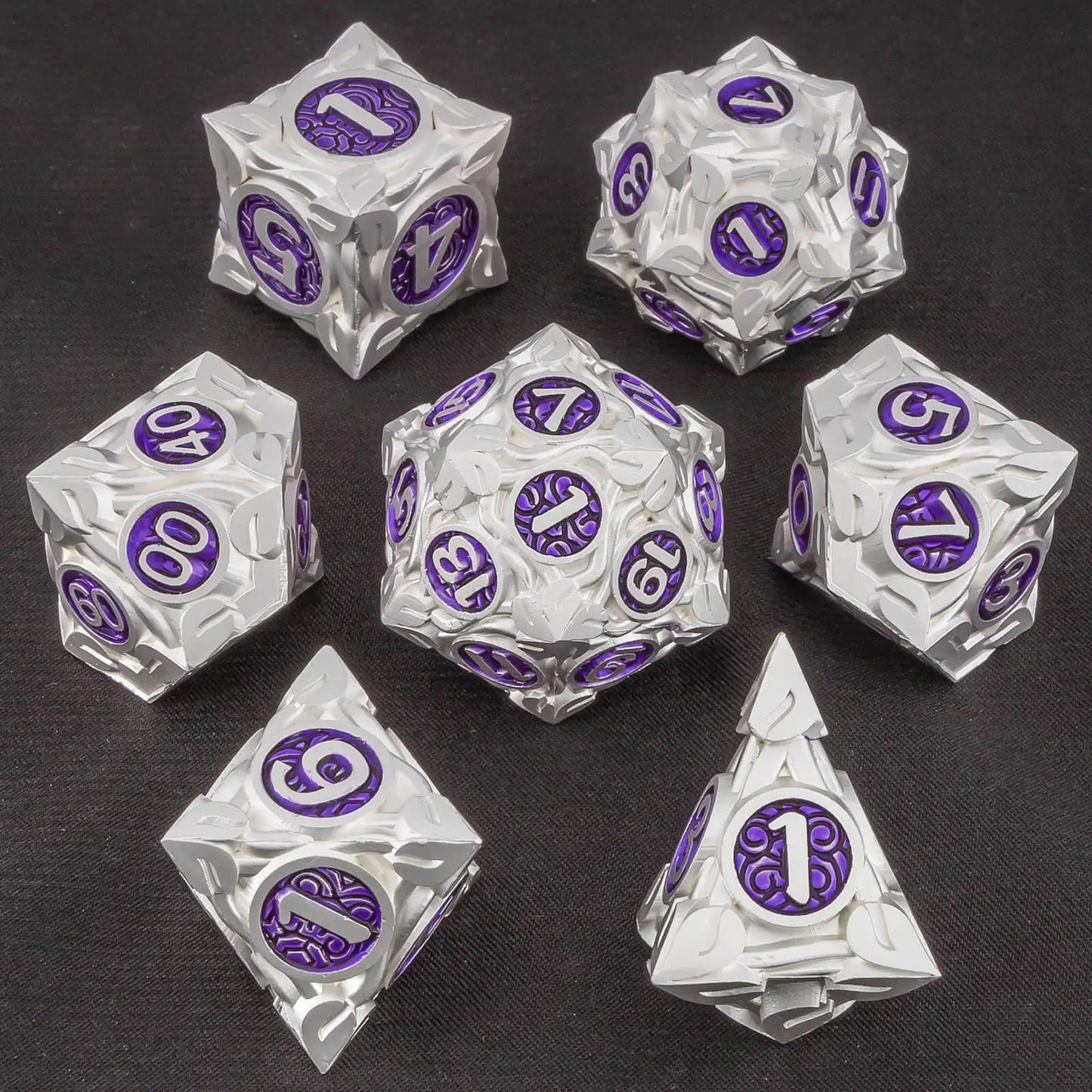 A set of silver metallic polyhedral gaming dice with purple circular faces displaying white numbers, arranged on a dark textured background.
