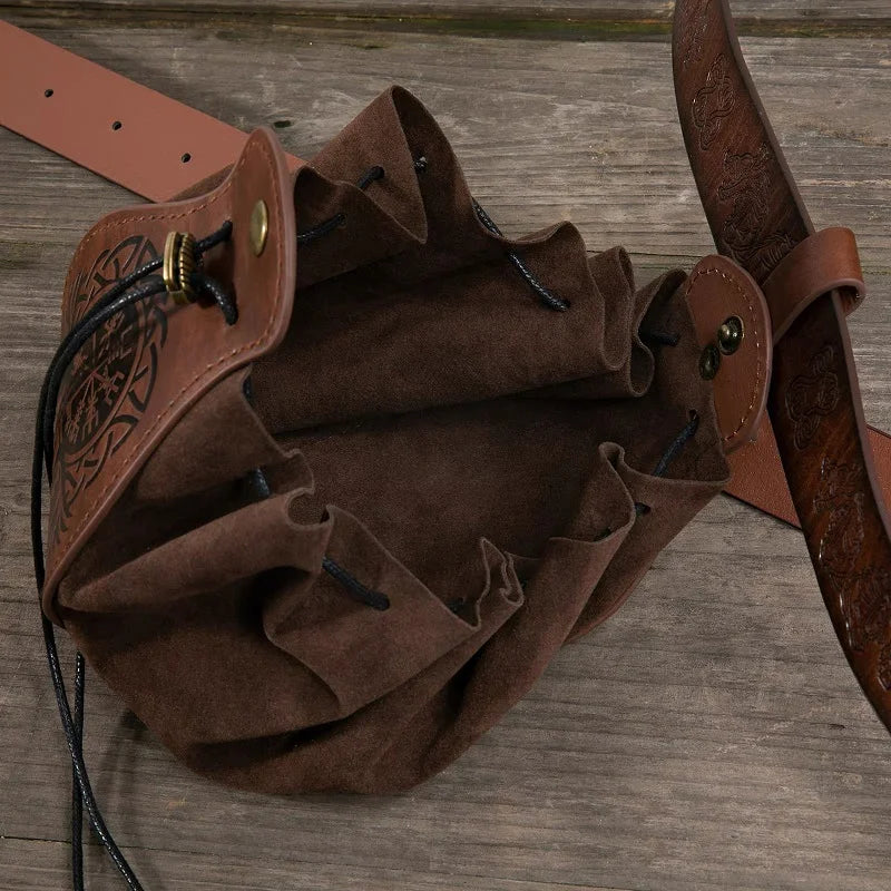 A brown leather and suede bucket bag with an embossed tree design on the side, shown on a rustic wooden surface with its strap partially visible.