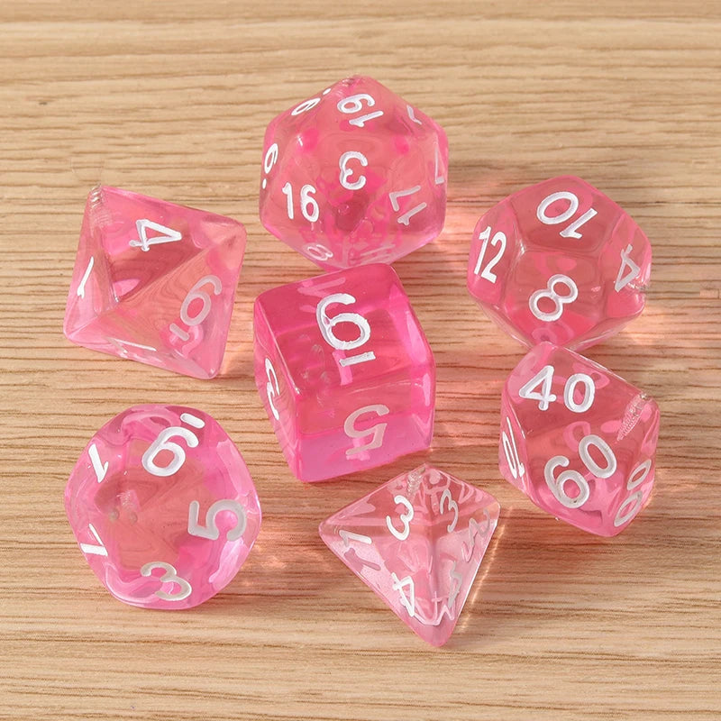 Set of pink polyhedral dice with white numbers on a wooden surface
