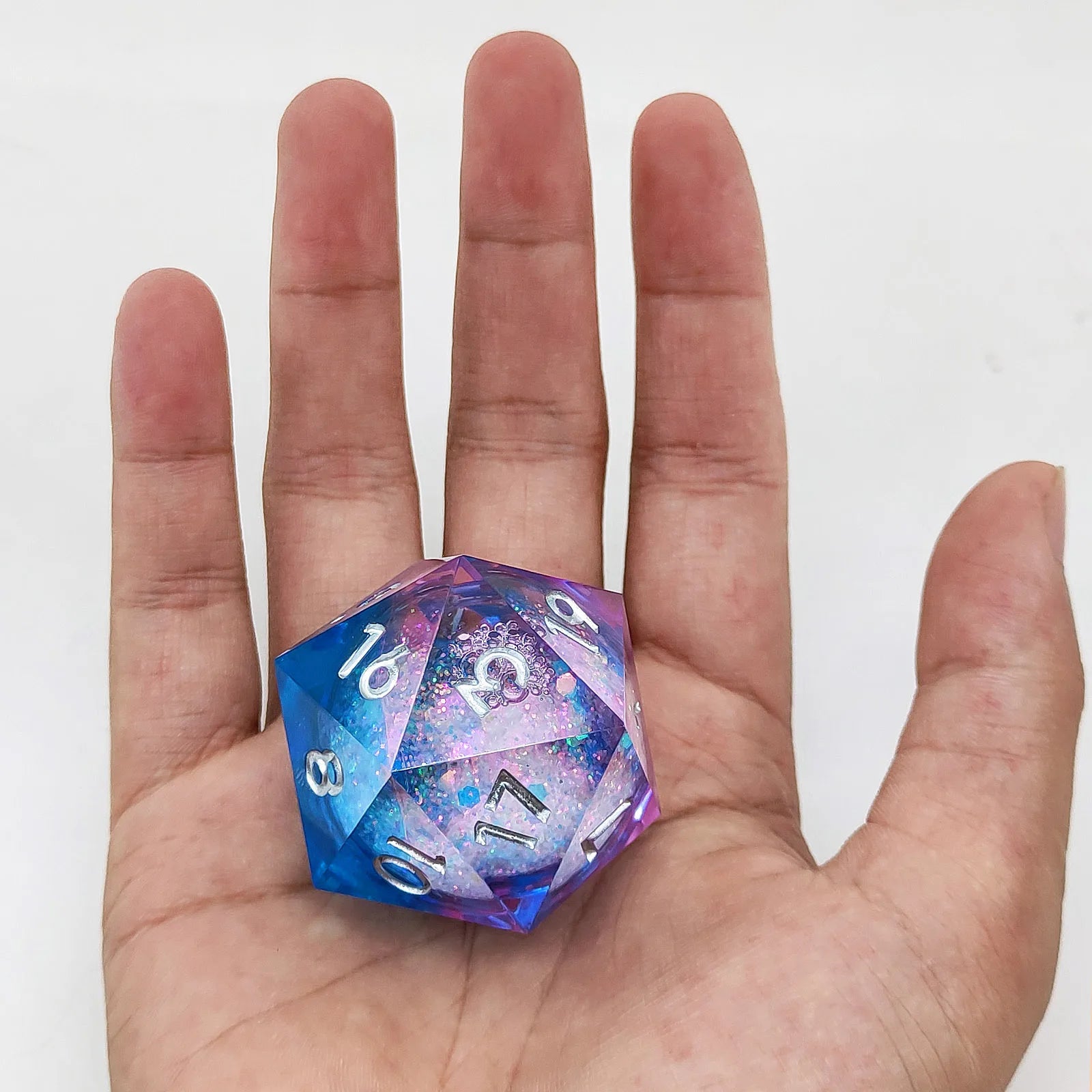 D20 polyhedral dice with blue and purple colors held in a hand against a white background