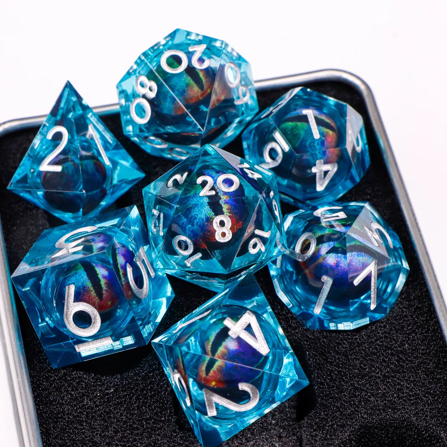 A set of blue translucent ttrpg dice with silver numbering. Inside each die there is a liquid core, containing a rainbow fantasy eye staring upwards.