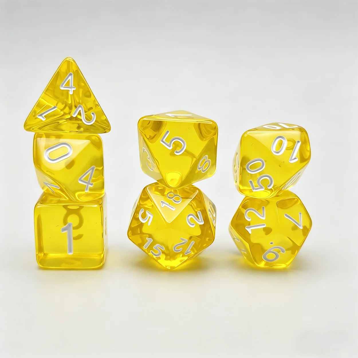 A set of translucent yellow polyhedral dice with white printed numbers, arranged on a clean white background.