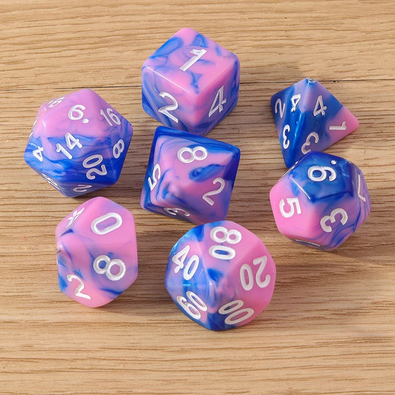 Set of blue and pink dice with white numbers on a wooden surface