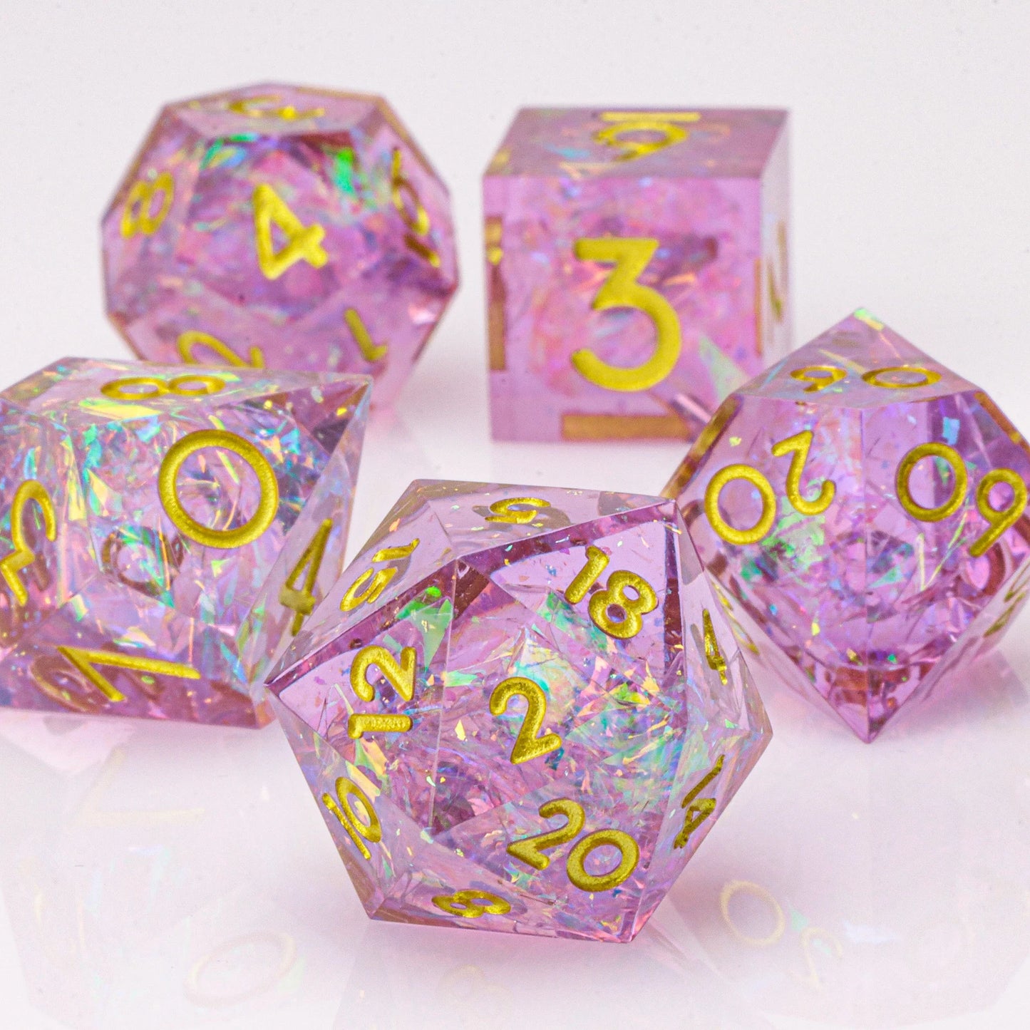 Set of pink polyhedral dice with gold numbers on a white background