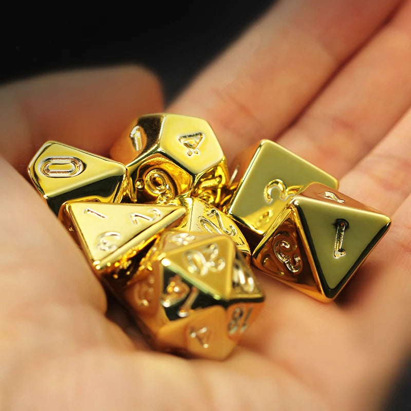 Gold metal dice set held in a hand against a blurred background
