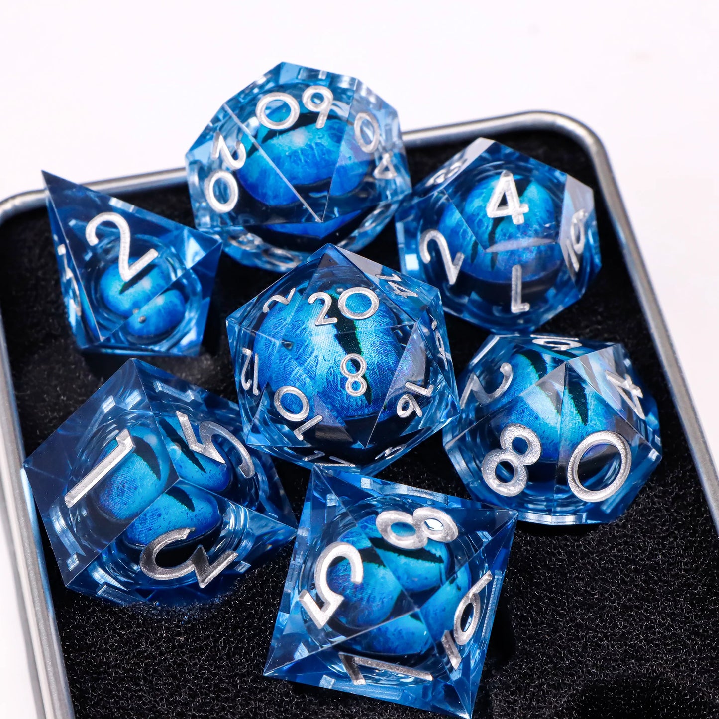 A set of blue translucent ttrpg dice with silver numbering. Inside each die there is a liquid core, containing a fantasy eye staring upwards.