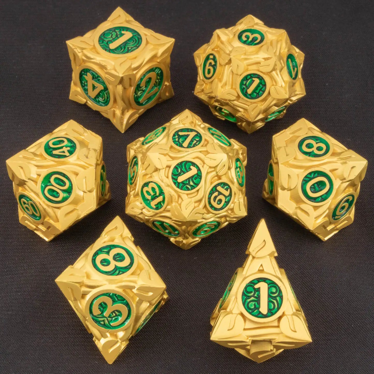 A set of metallic gold polyhedral gaming dice with embossed floral patterns and green circular faces displaying white numbers, arranged on a dark textured background.