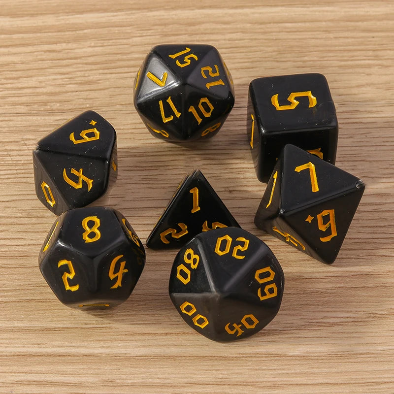 Black polyhedral dice with yellow numbers on a wooden surface