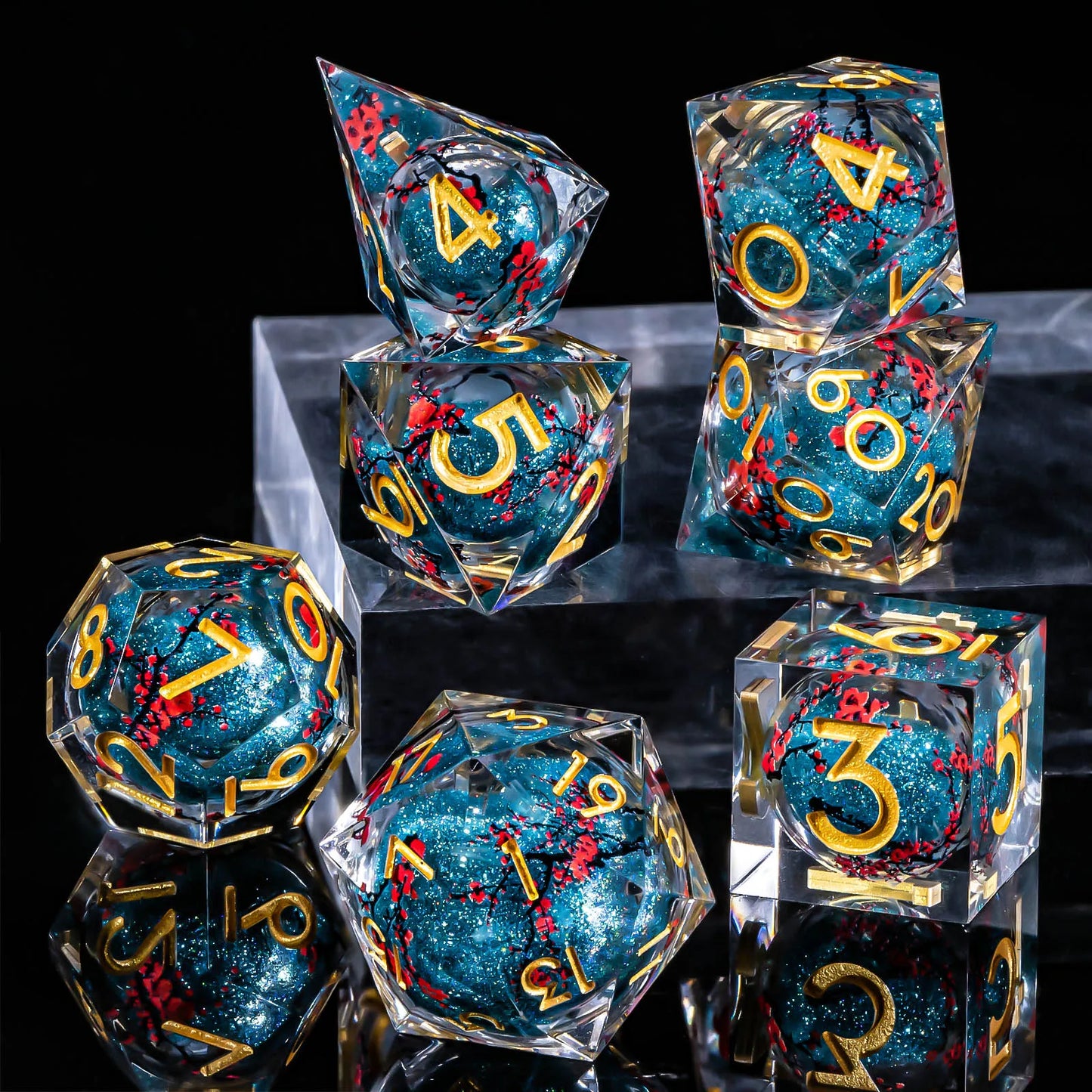 A set of transparent polyhedral dice filled with glittery teal-blue liquid core and decorated with gold numbers and red floral details, arranged on clear acrylic blocks against a black background.