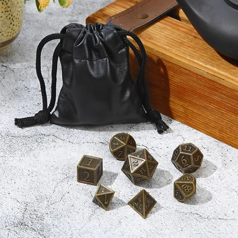 Set of bronze dice with a black drawstring bag on a textured surface.