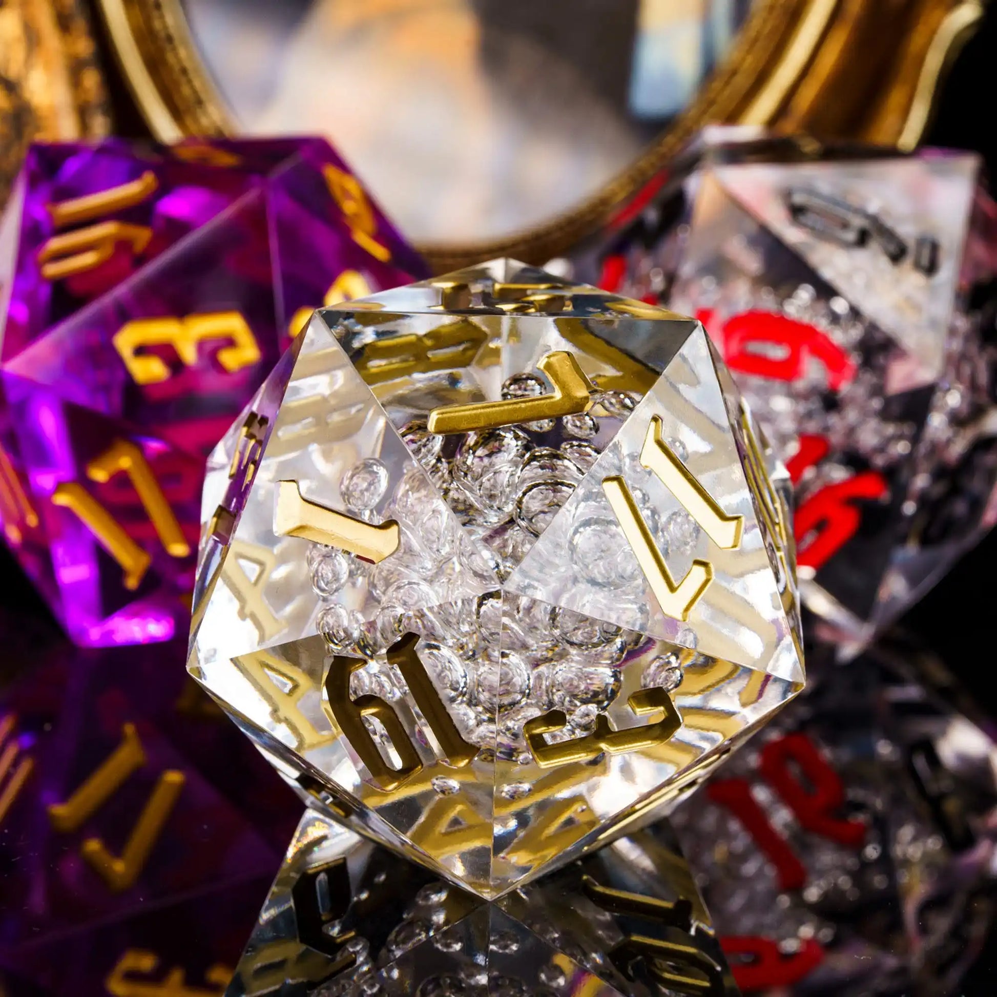A clear acrylic d20 die showing gold numbers, surrounded by other translucent polyhedral dice with red, purple, and clear numbers in the background.