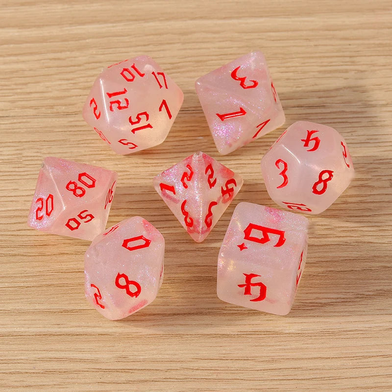 Set of pink dice with red numbers on a wooden surface