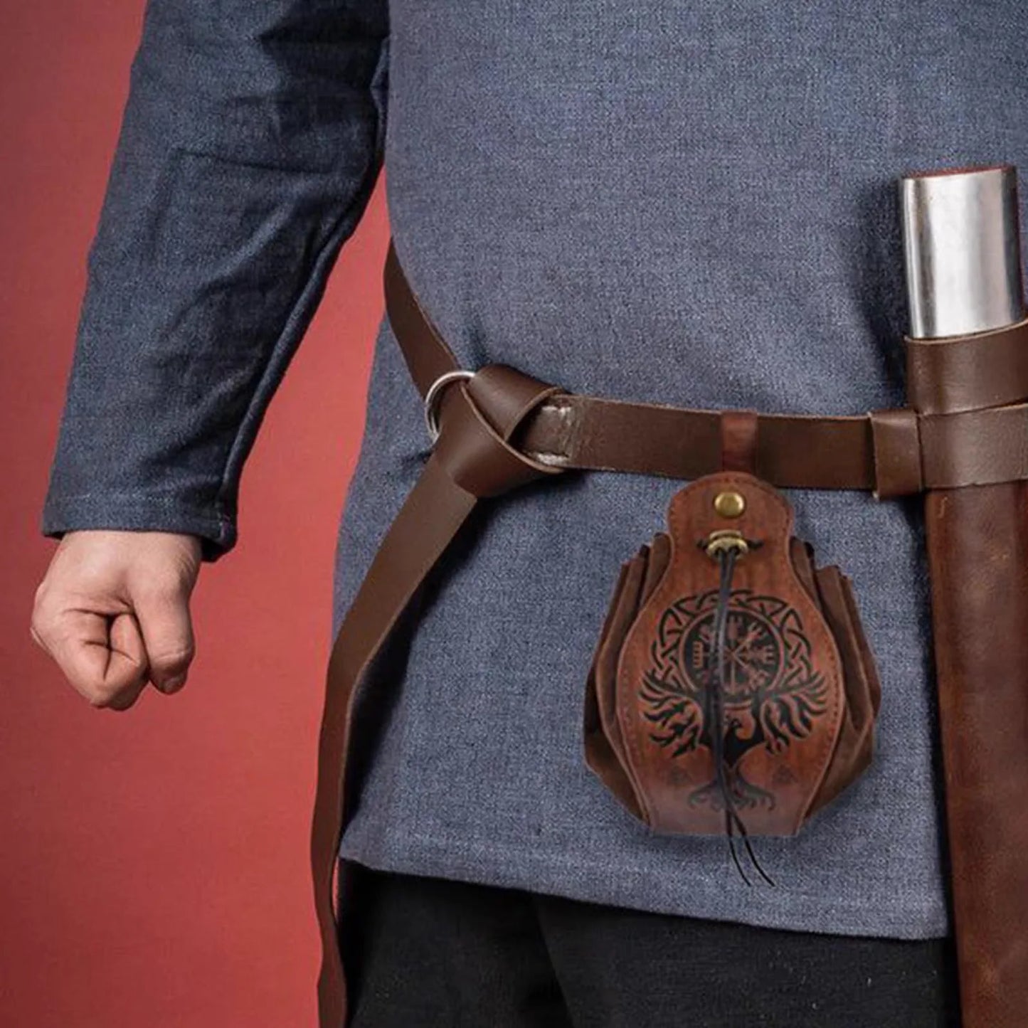 Person wearing a blue garment with a brown leather belt and decorative pouch against a red background