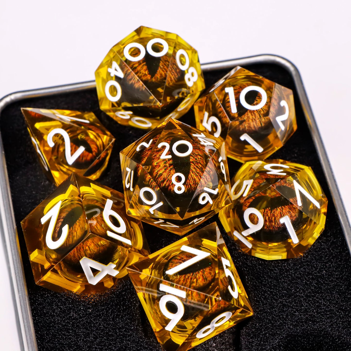 A set of yellow translucent ttrpg dice with white numbering. Inside each die there is a liquid core, containing a fantasy eye staring upwards.