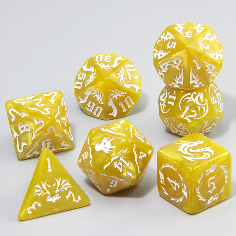 A set of yellow polyhedral gaming dice with white dragon illustrations, arranged on a light gray background.